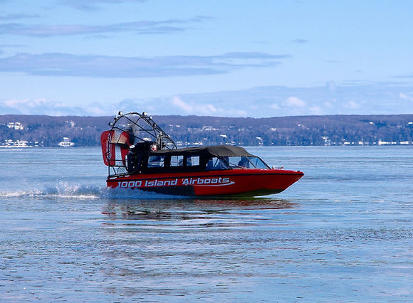 Red ice-water airboat on water with mountains in background