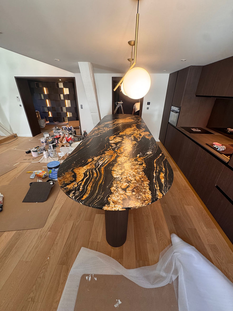 Îlot de cuisine en pierre naturelle veinée noire et dorée, installé lors d’une rénovation d’appartement à Lyon, avec finitions haut de gamme et mobilier sur mesure.