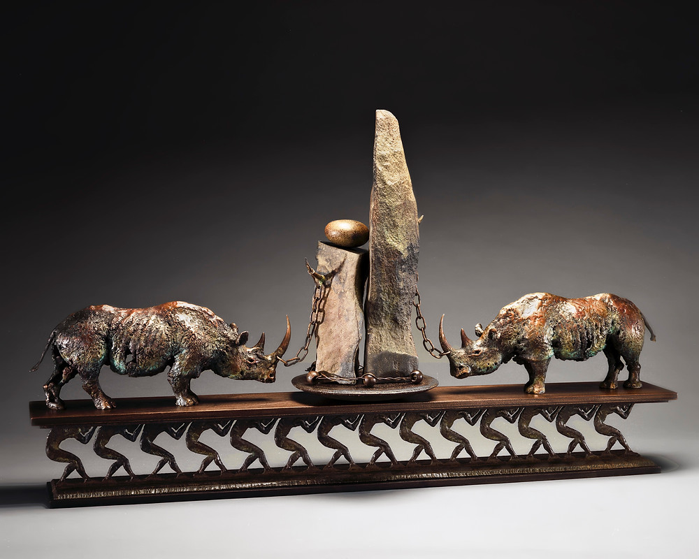 2 bronze rhinos chained to a stone alter, all being held up on the backs of laborers