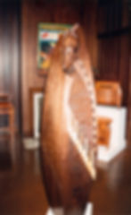Carved walnut and maple obelisk chest with piano keys on door and stylized African head and hand showing out top of door.