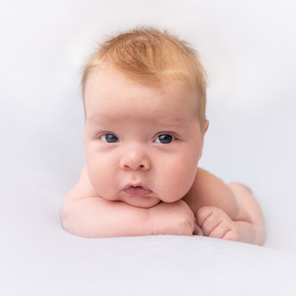 Baby med rødt hår som ligger på magen