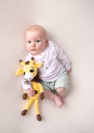 Baby ligger med giraffleke