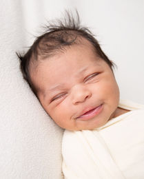 Nyfødt baby med mørkt hår som smiler