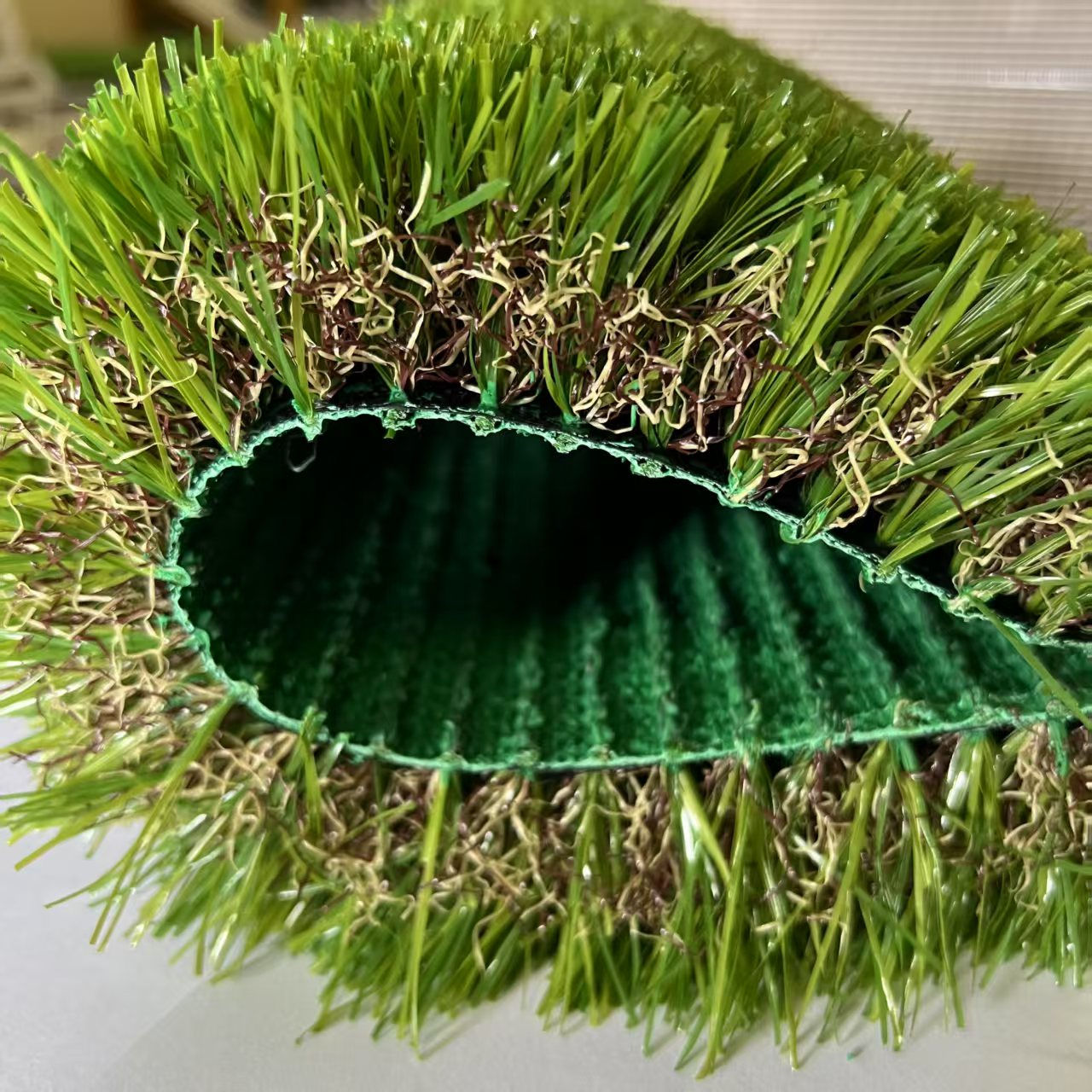 Close-up roll of lush green artificial grass showing backing