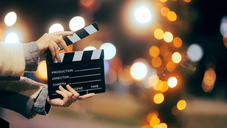 Someone holding a clapper board in front of festive lights.