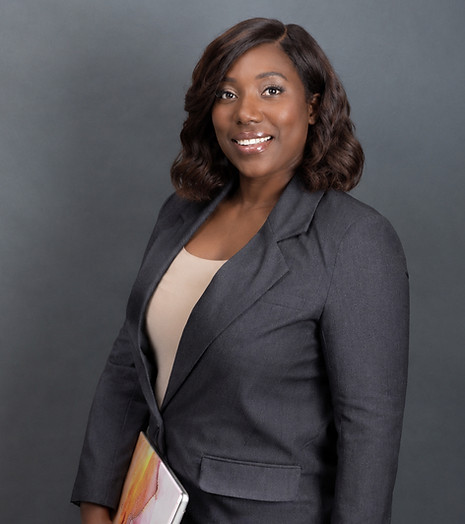 Selina Thompson smiling in a charcoal suit while holding a laptop.