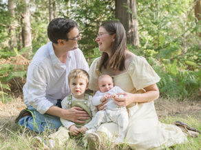 Parents cuddling their toddler and newborn during an outdoor family photoshoot in Oxford