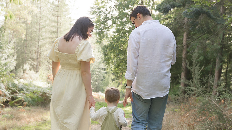 A family strolls hand in hand down a sunlit forest path, capturing a moment of togetherness and serenity.