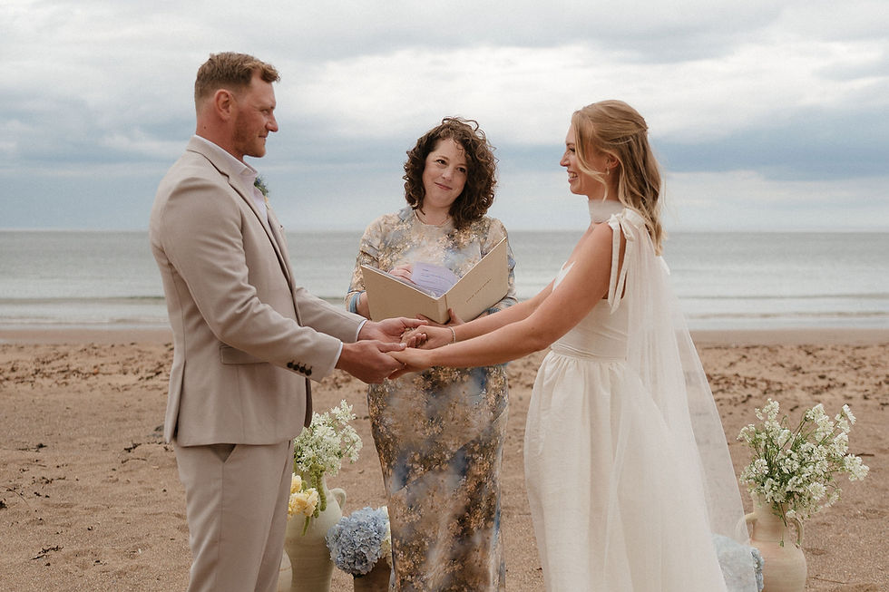 Bride and groom holding hands during beach ceremony led by celebrant, showcasing relaxed destination wedding trends 2026.