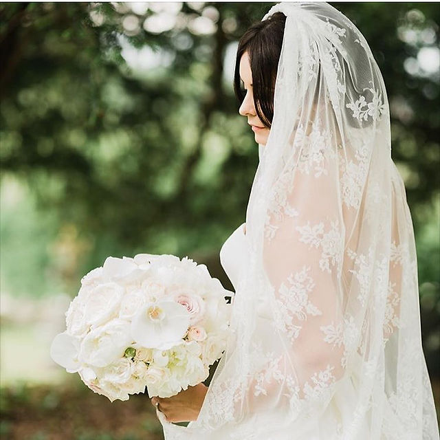 Bride holding white bouquet beneath a delicate lace wedding veil — vintage-inspired bridal look aligning with lace veil trends 2026.