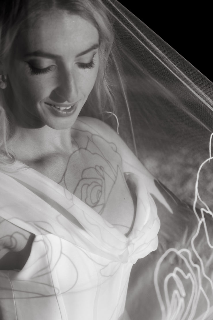 A bride under a veil with large scale embroidery showcasing how design size and complexity can impact the cost of a wedding veil