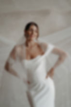 Bride wearing a custom pearl-embellished veil with scattered embroidery details, showcasing luxurious pearl bridal hair accessories that add timeless elegance to her wedding look.