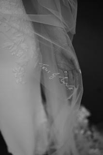 Close-up of handwriting embroidery on a veil saying “love you,” resting over the bride’s hand – a tender detail woven into the day.