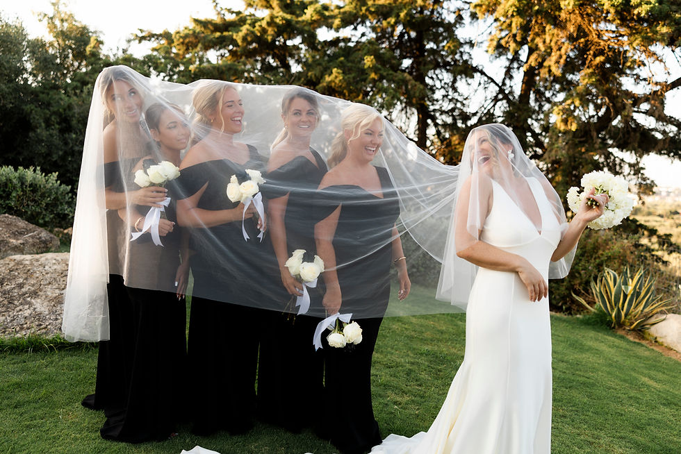 Real bride Charley laughing with her bridesmaids beneath a flowing tulle veil — natural wedding veil photography capturing candid, joy-filled moments.