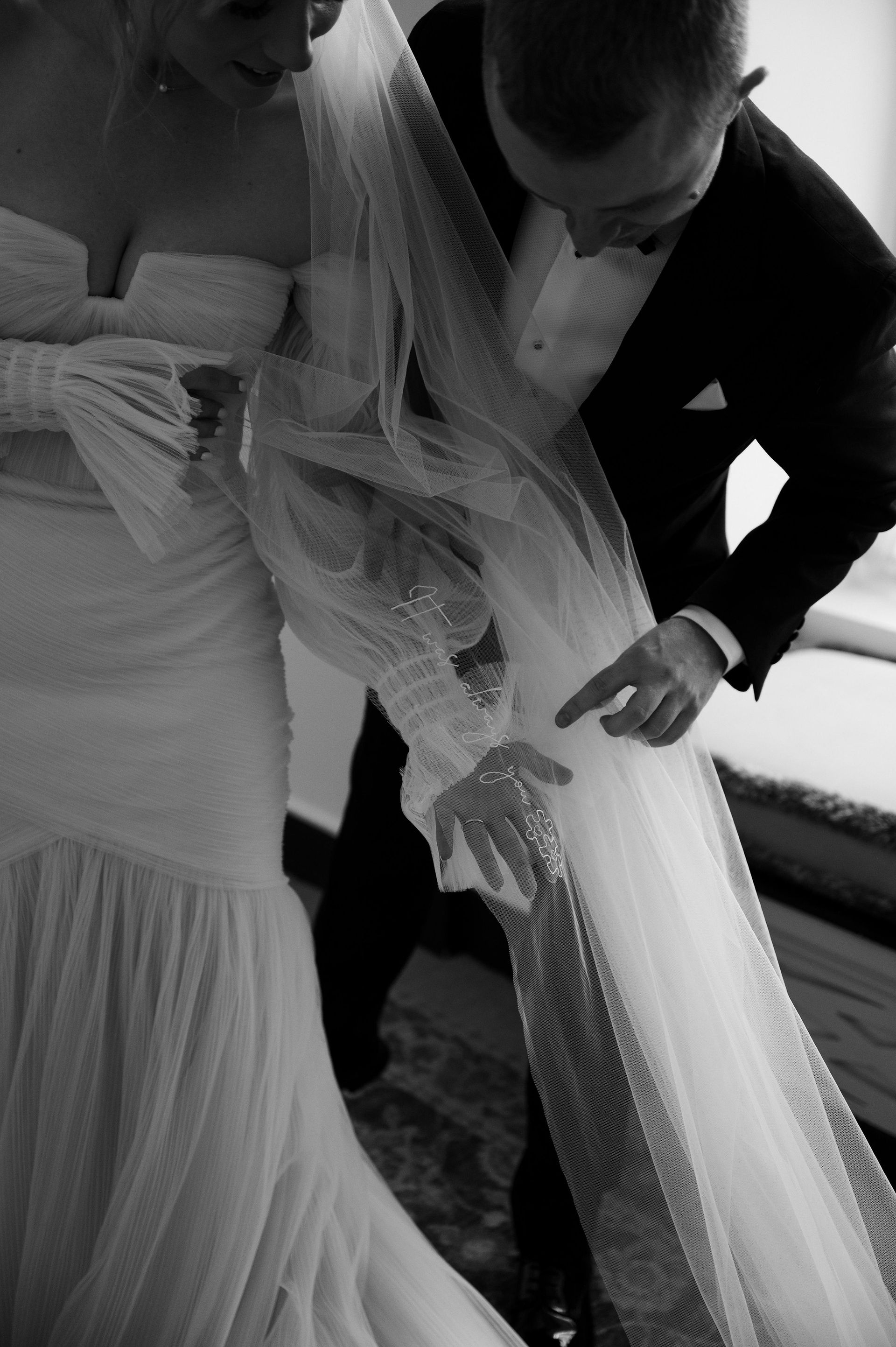 A couple sharing an intimate moment, showcasing a bespoke civil ceremony wedding veil with personalised embroidery.