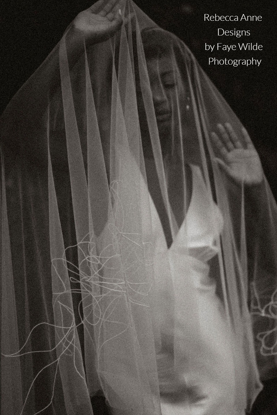 A bride draped in a dramatic embroidered wedding veil, featuring abstract floral detailing along the edge. A statement piece embracing the 2024 wedding veil trends.