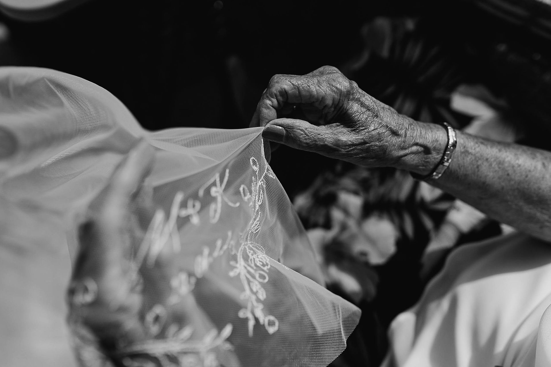 Close up of hands admiring personalised details on embroidered Rebecca Anne veil