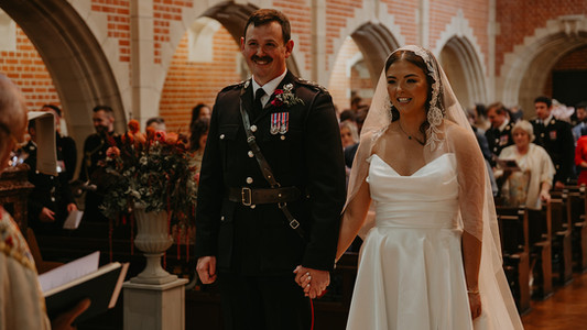 Military bride and groom holding hands during Royal Navy wedding ceremony at BRNC Dartmouth chapel.