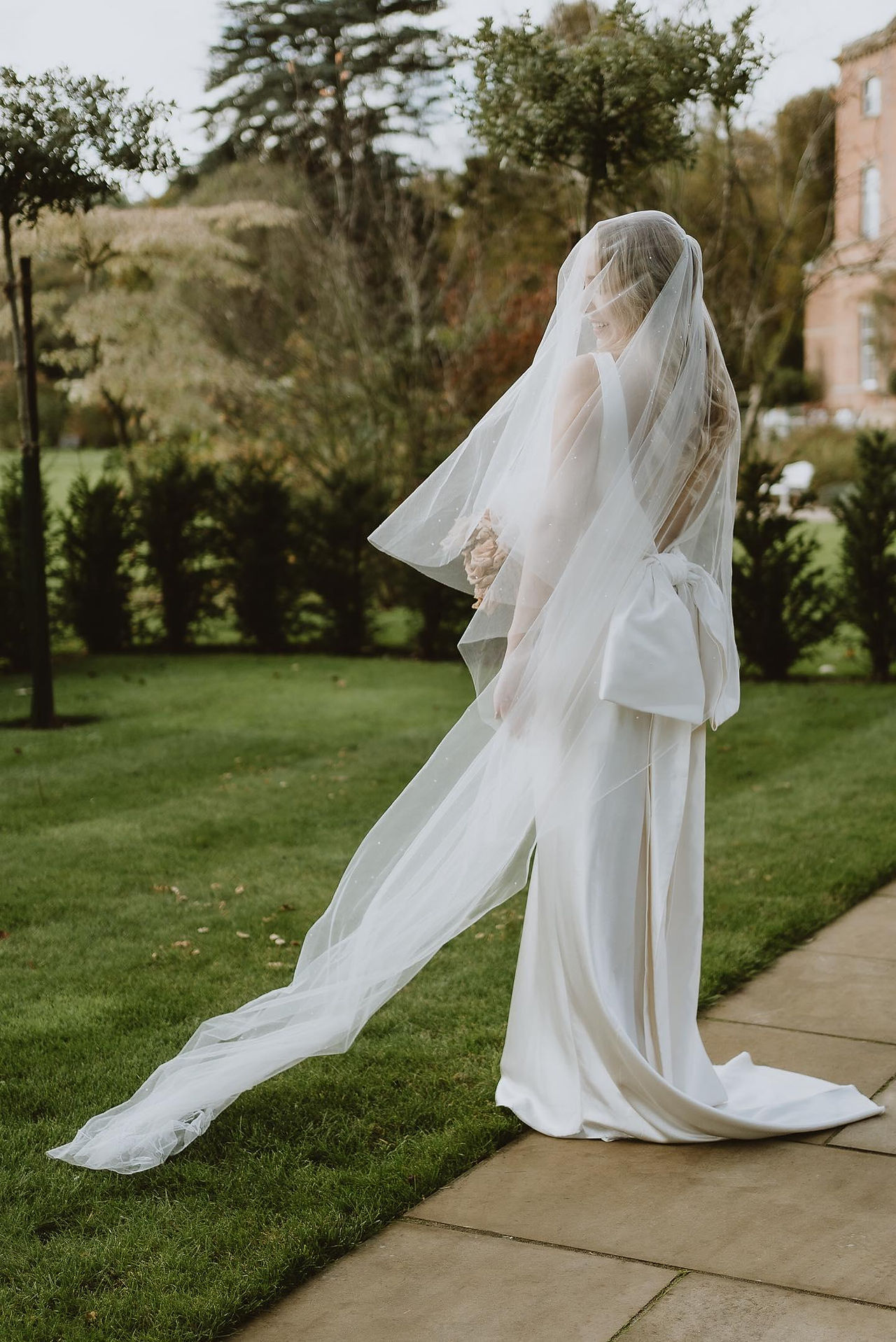 A full length portrait of a bride wearing a sparkly wedding veil which Rebecca Anne predicts will be a 2024 wedding trend