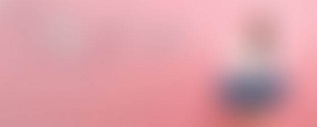 Eine junge Frau sitzt nachdenklich auf einem Hocker mit ihrem Laptop in der Hand