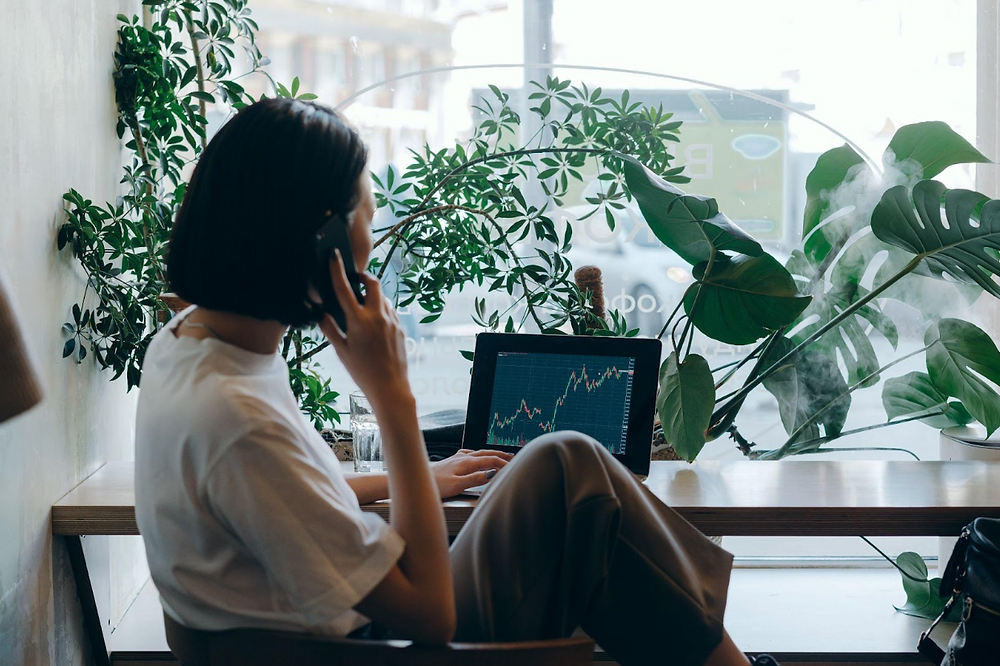 Woman on the phone looking at stocks on her computer.