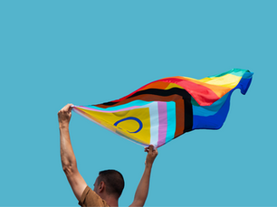 Person waving aprogressive Pride flag with blue sky in the background