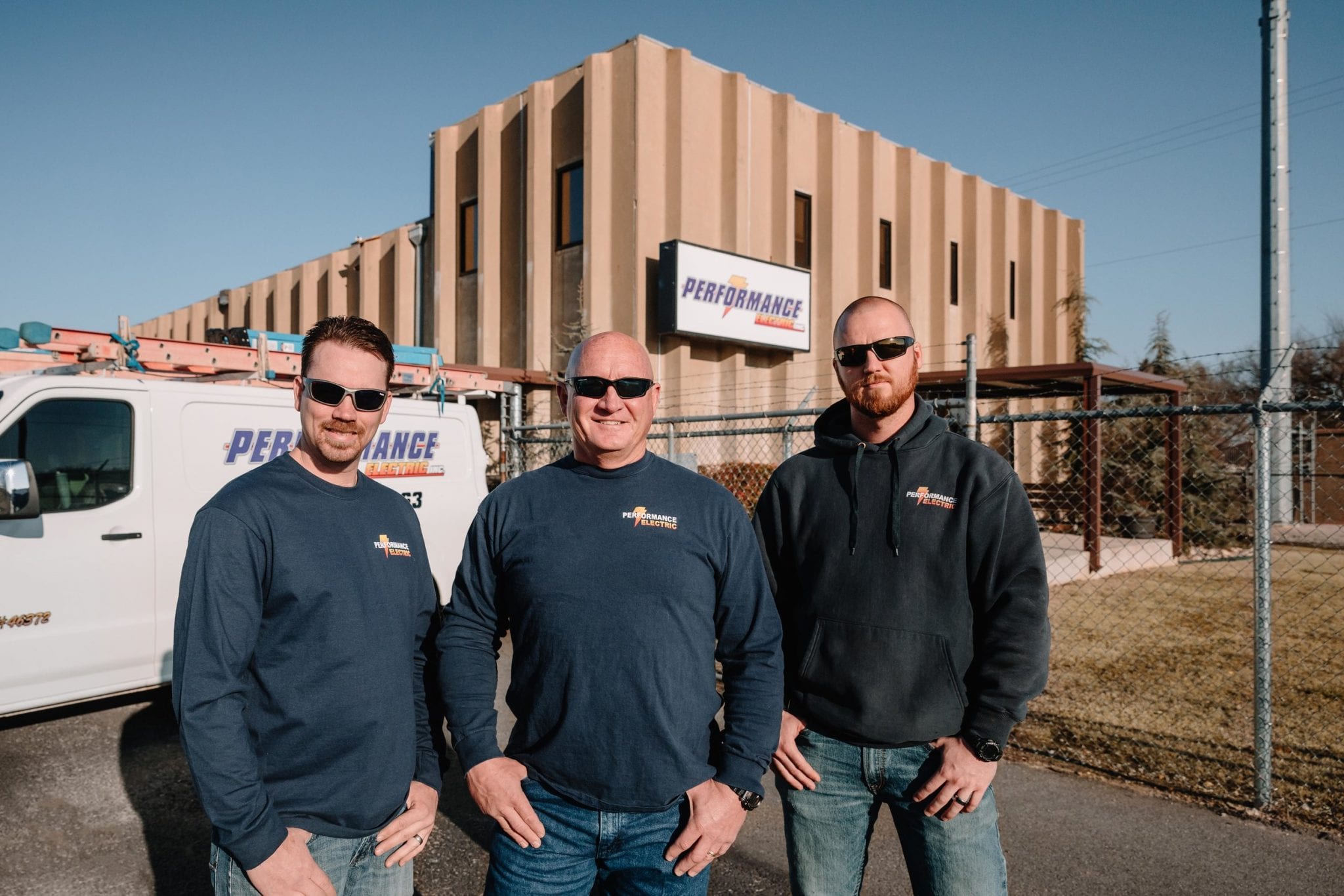 Performance Electric team of electricians standing in front of company van and office in Oklahoma.