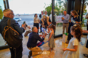 Youngest travelers receive a warm welcome with flags and candy