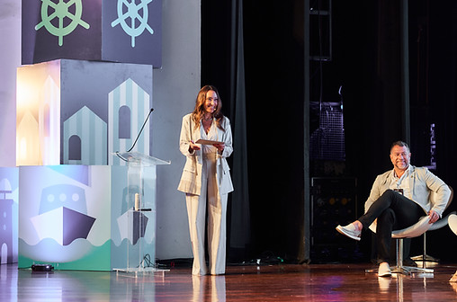 Juliana Karam como mestre de cerimônias em palco decorado com cenografia de evento corporativo