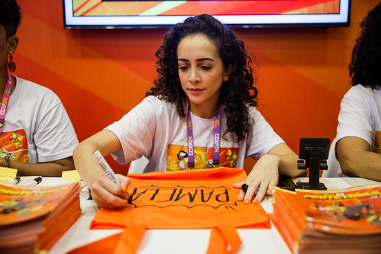 Ju Souza personalizando ecobag laranja com caligrafia em evento corporativo