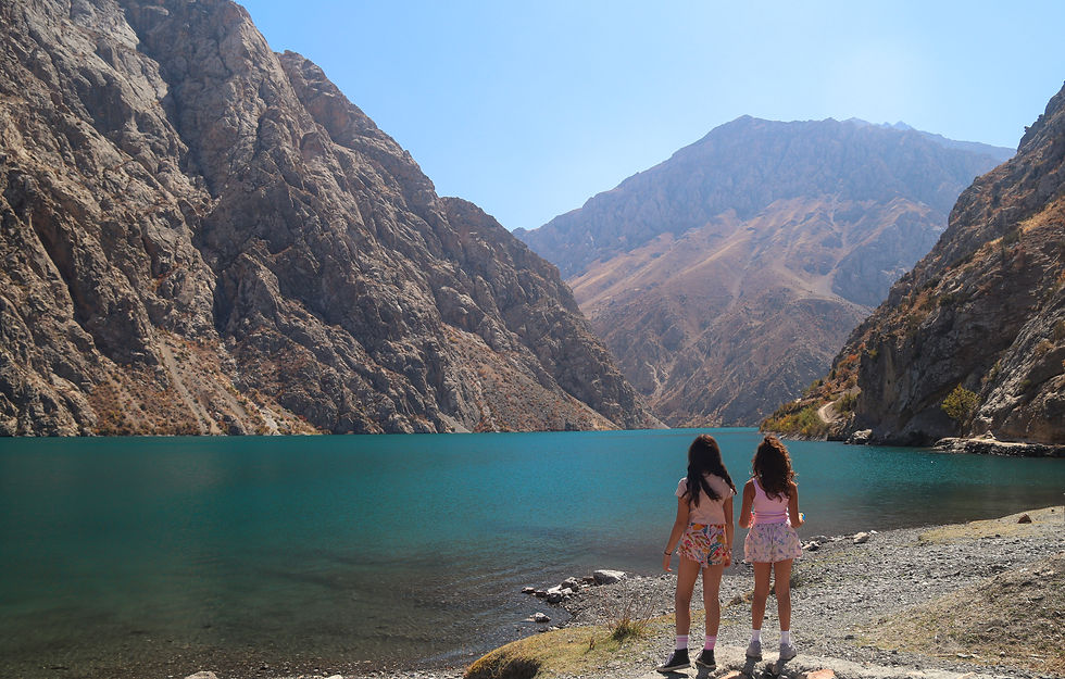 Two girls looking over a blue lake and mountains in Tajikistan