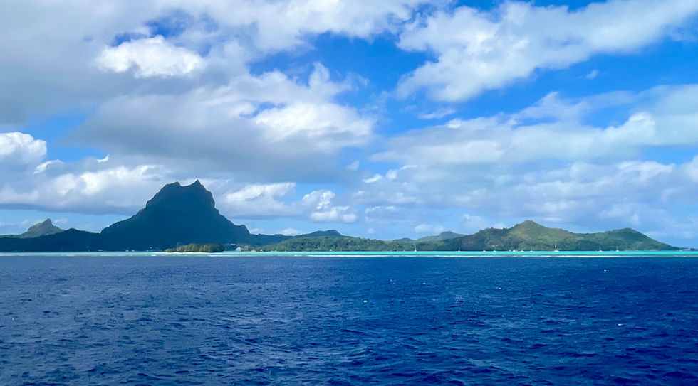 Bora Bora Island from a distance, blue water, blue sky, jaggered volcanic peak