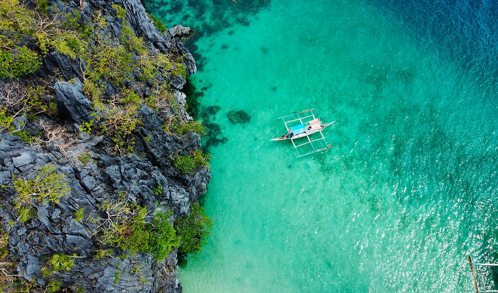Aerial view of a boat in turquoise water, near limestone cliffs, Philippines.