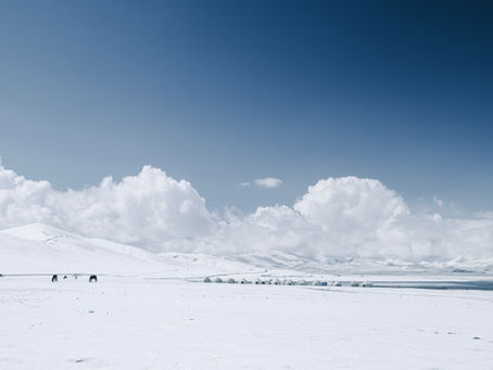 Snowy landscape with yurts and horses