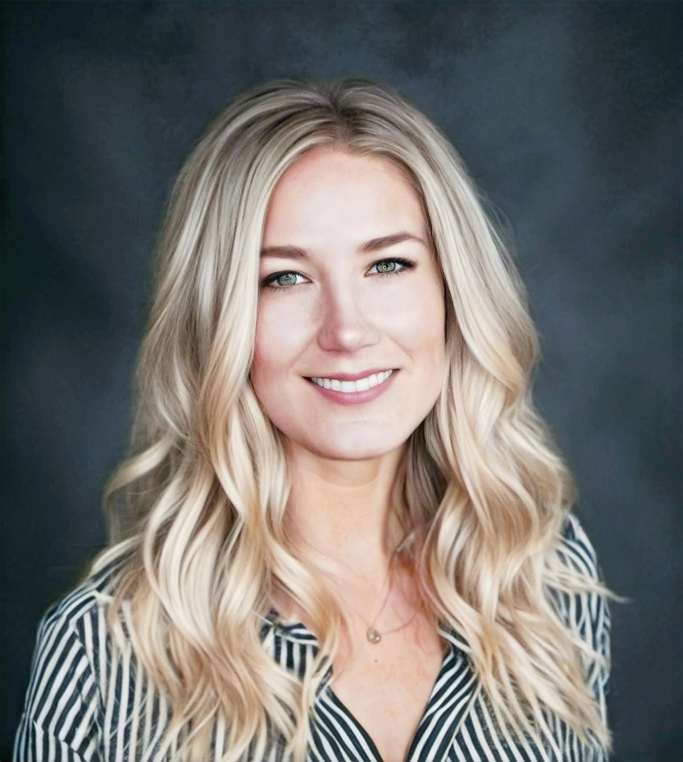 Woman with long blond hair an on stripped white and black shirt wearing a necklace while smiling