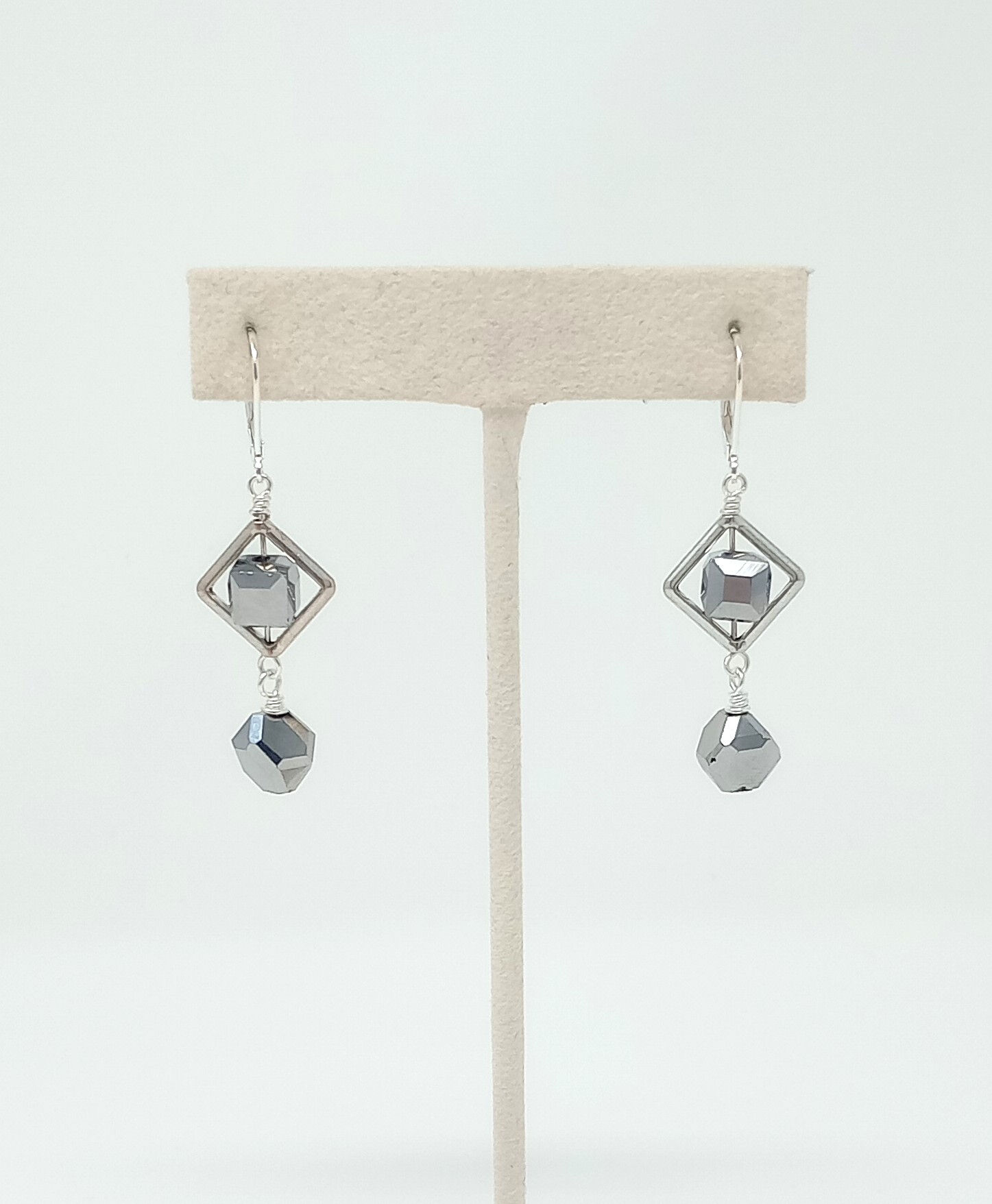 Handcrafted earrings in silver on silver tones. Silver crystals sparkle from within a geometric diamond frame.