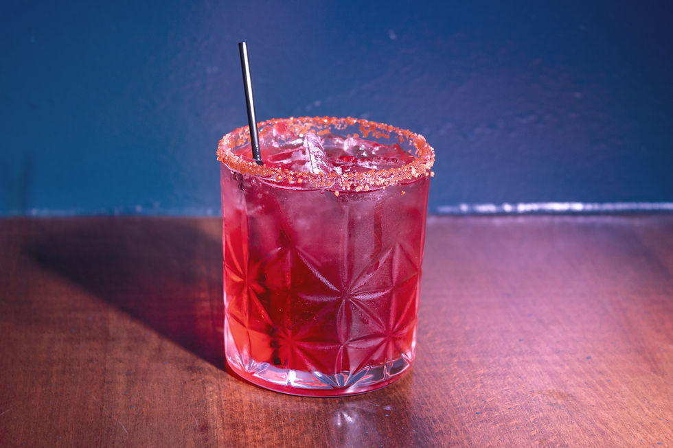 Vibrant red cocktail in faceted glass, sugar-rimmed, with black straw.