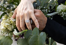 Couple showing their wedding rings over a white floral bouquet
