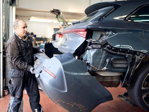 Mechatroniker setzt Autoteil ran