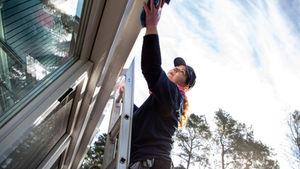 Frau reinigt Dach von Wintergarten