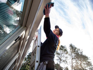 Frau reinigt Dach von Wintergarten