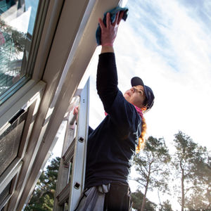 Frau reinigt Dach von Wintergarten