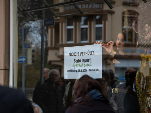 Frau zieht Plakat von Schaufenster ab