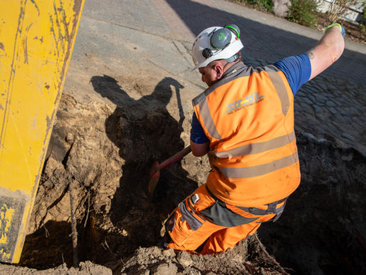 Ein Bauarbeiter schaufelt auf einer Baustelle ein Loch