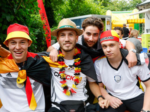 Vier junge Männer in Deutschlandoutfit beim Fußball gucken.