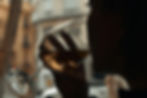 Person sipping from a wine glass indoors, blurry cityscape outside. Warm lighting creates a calm, intimate mood.