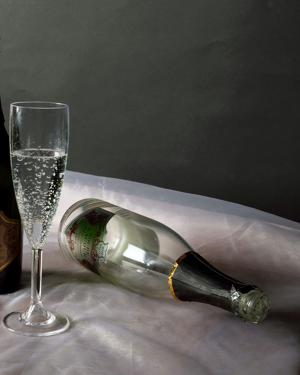Champagne flute with bubbly drink beside a lying bottle on a silky, reflective surface and dark background. Elegant and celebratory mood.