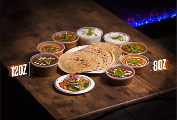 Punjabi thali with curries, rotis, rice, and sides on a wooden table
