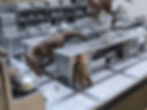 Dinosaur raptors stalking a person in a miniature kitchen.