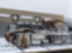 Diorama of two raptors in a kitchen with a person hiding.